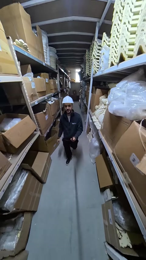 Employee walks warehouse aisle lined with packaged polyurethane products