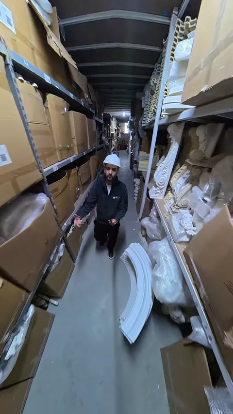 Employee walks past shelves holding white polyurethane column pieces