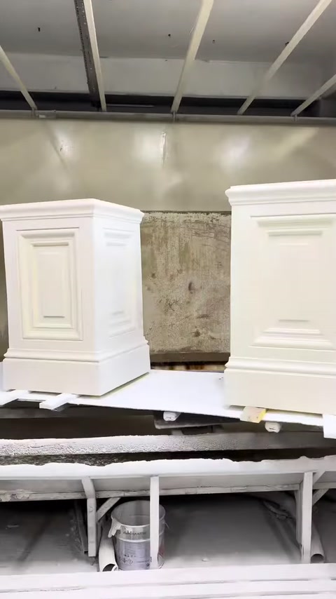 Two polyurethane pilaster column capitals stand side by side in the production area