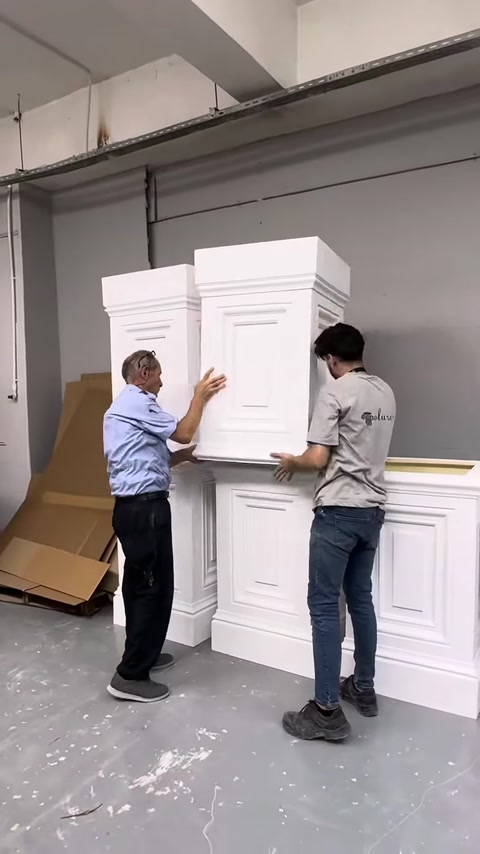 Two large pilaster elements are placed on top of each other for inspection