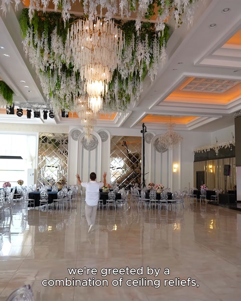 Ampia vista della sala con rilievi a soffitto, colonne e lampadari in cristallo