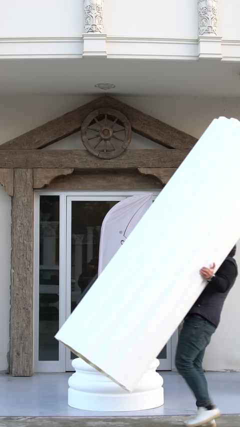 A long fluted panel is held at an angle at the installation point near the building entrance.