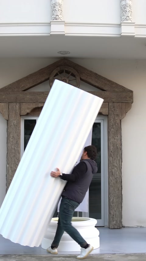 A worker aligns the bottom edge of the fluted shaft with the round base.