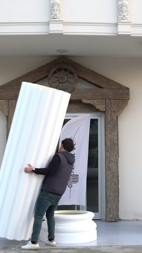 The angled column cover is being prepared to stand upright on the pedestal.