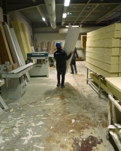Worker carries raw polyurethane material sheets across warehouse floor