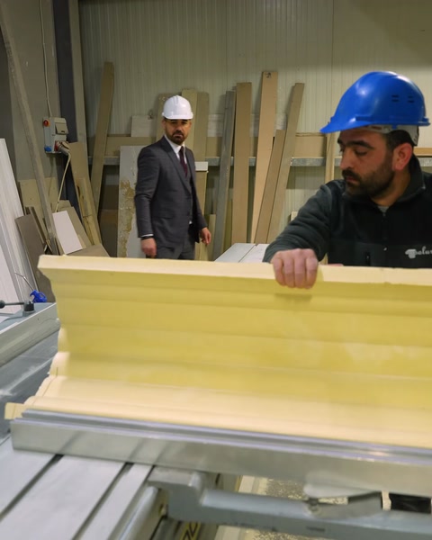 Craftsman inspects raw yellow polyurethane cornice profile closeup