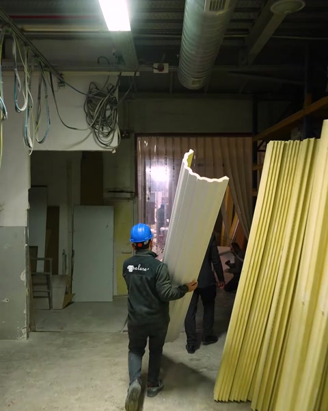 Worker carries raw yellow polyurethane column profile through warehouse
