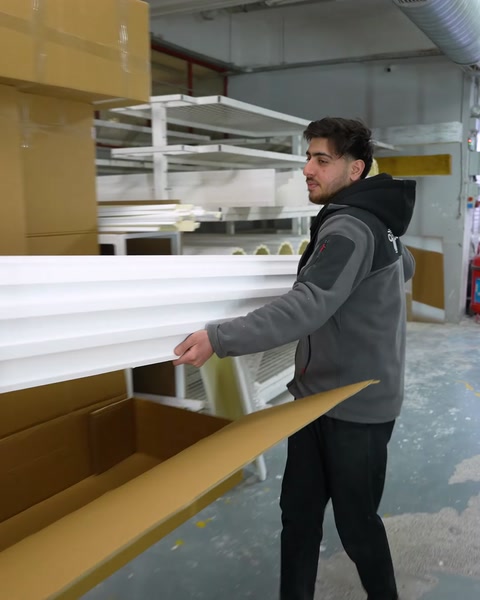 Worker packs finished polyurethane profile into cardboard box
