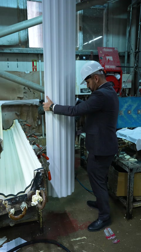 Worker holds white polyurethane column profile near machine