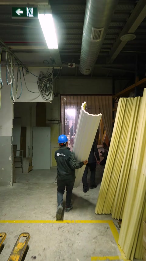 Worker carries raw yellow polyurethane column profile through warehouse