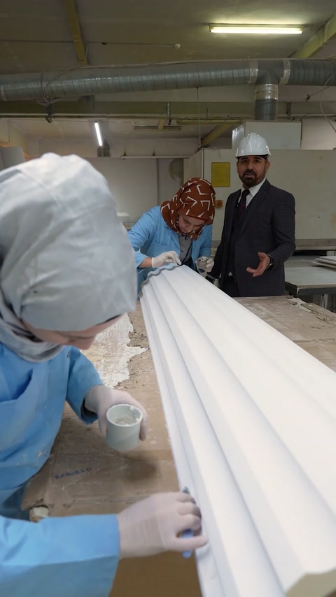 Workers hand-finish white polyurethane cornice profile surface detail
