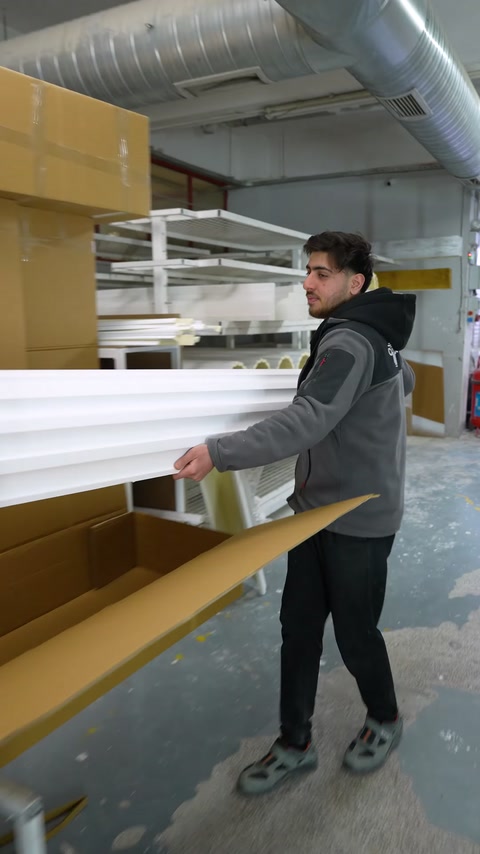 Worker packs finished polyurethane profile into cardboard box