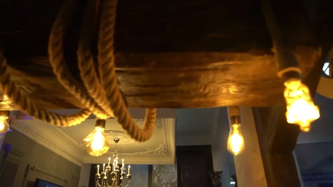 Primo piano delle travi del soffitto con dettagli effetto corda e lampadine sospese