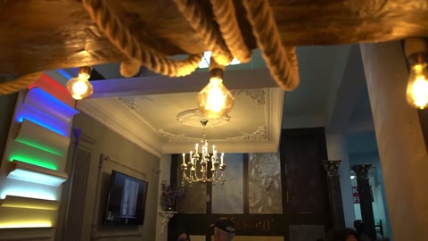 Sono visibili i strati del soffitto colorati, le travi con corde e gli elementi di illuminazione sospesi