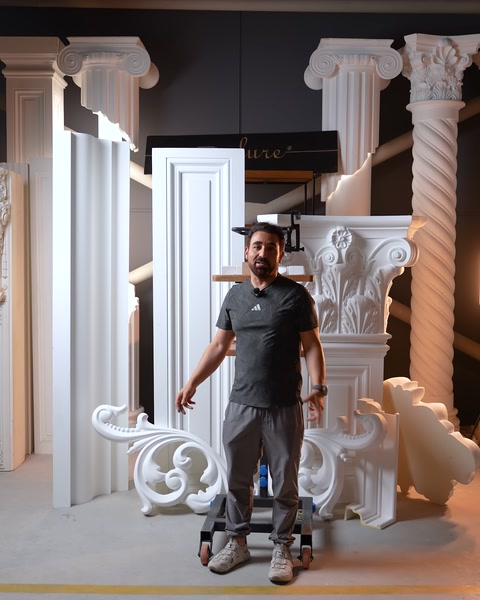 Operaio in posa accanto a cornice, colonna e componenti ornamentali