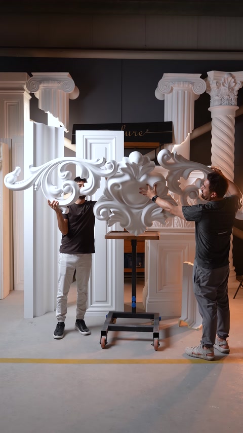 Due artigiani tengono un grande pezzo ornamentale per l'installazione.