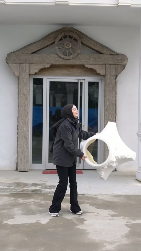 Il presentatore tiene una sezione di capitello in poliuretano bianco nel cortile.