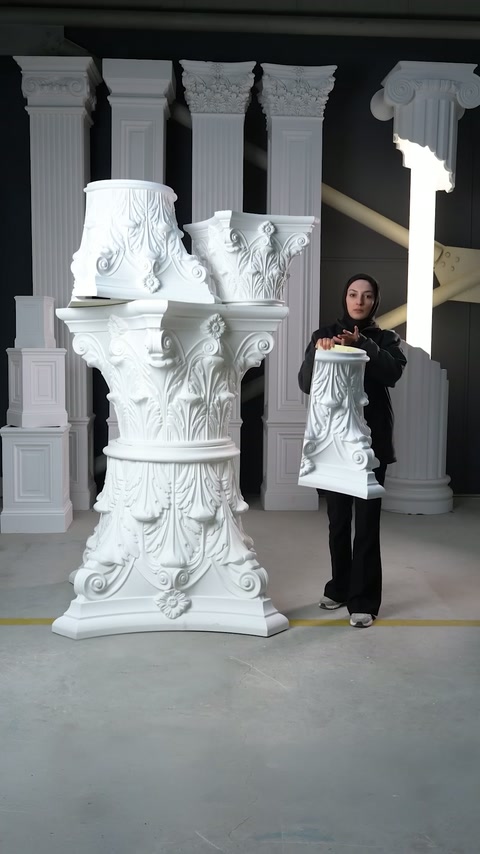 Il presentatore mostra una sezione di capitello diviso e alto accanto ai componenti decorativi impilati.