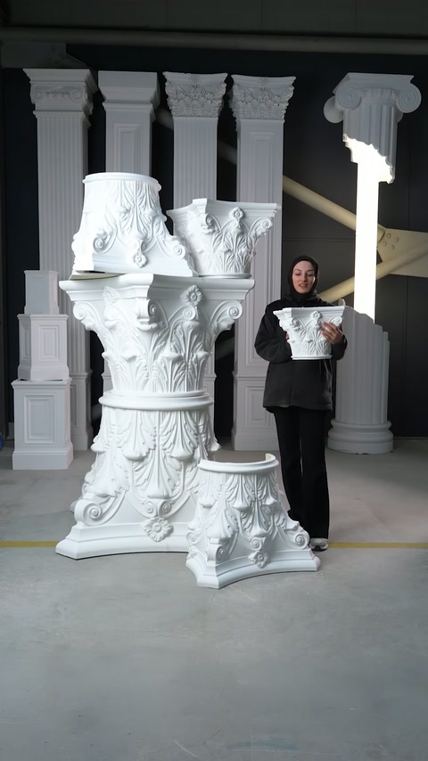 Un mezzo capitello compatto viene tenuto accanto ai componenti di colonna ornamentali più grandi.