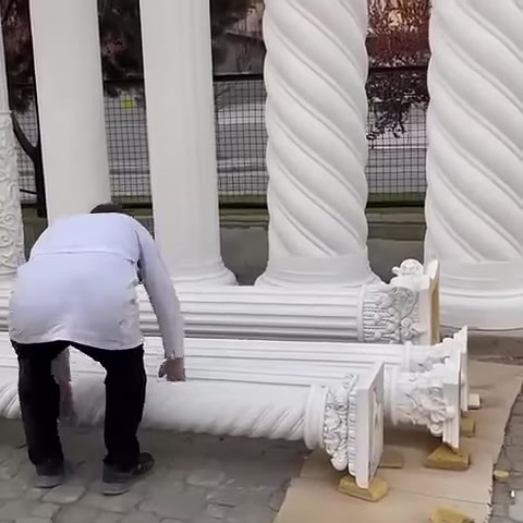 Un artigiano controlla un elemento di capitello decorato a terra