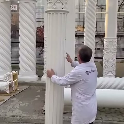 L'artigiano osserva da vicino la superficie scanalata della colonna in posizione verticale