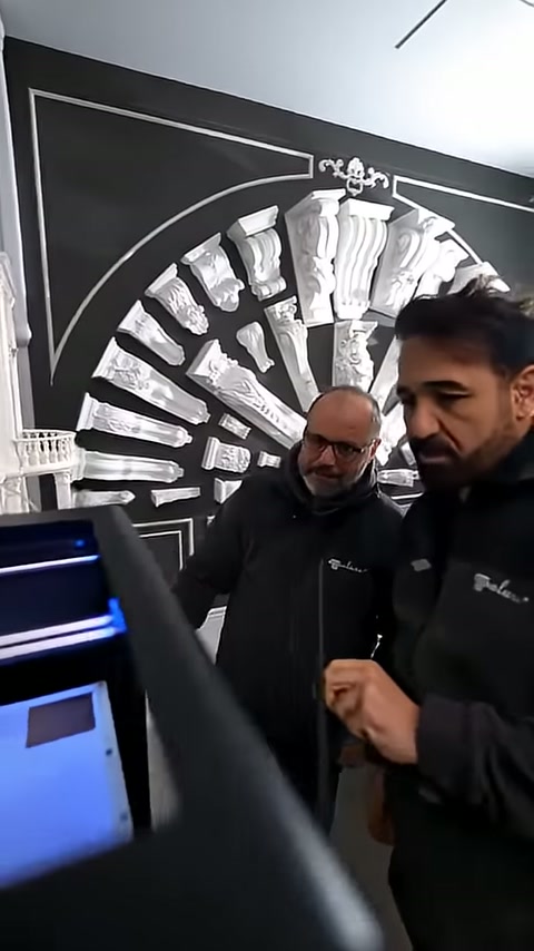 Two staff members jointly examine a small white piece on the device display board.