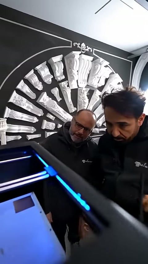 Booth staff inspect the production area of the blue-lit machine.