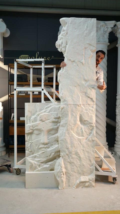Presenter peeks around assembled vertical relief panels in the showroom workspace.