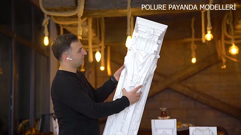 Carved pattern details on the upper section of the white column examined by hand