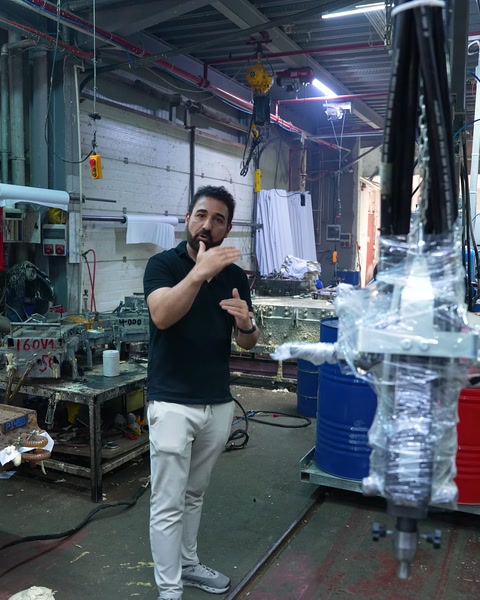 Worker explaining the polyurethane production process under the machine pipes