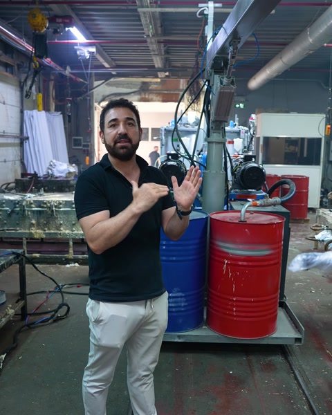 Worker giving an explanation in front of red and blue mixing barrels