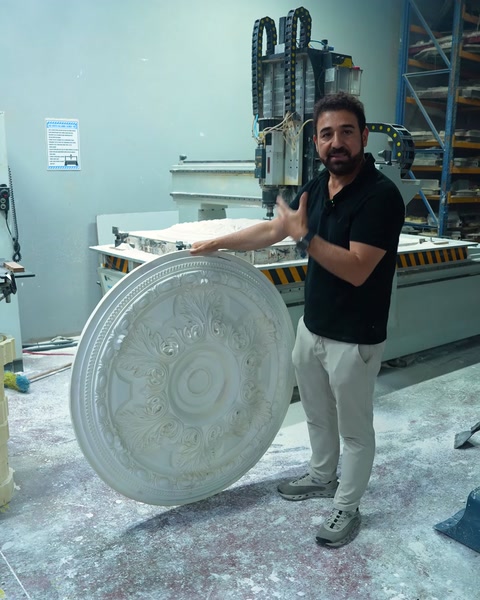 Worker showing a ceiling medallion next to the CNC machine