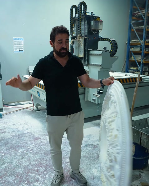 Worker displaying an oval ceiling medallion piece with both hands