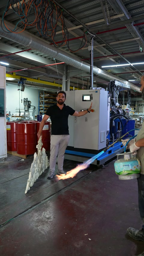 A workshop attendant introduces a fire test applied to an ornamental polyurethane element in hand.