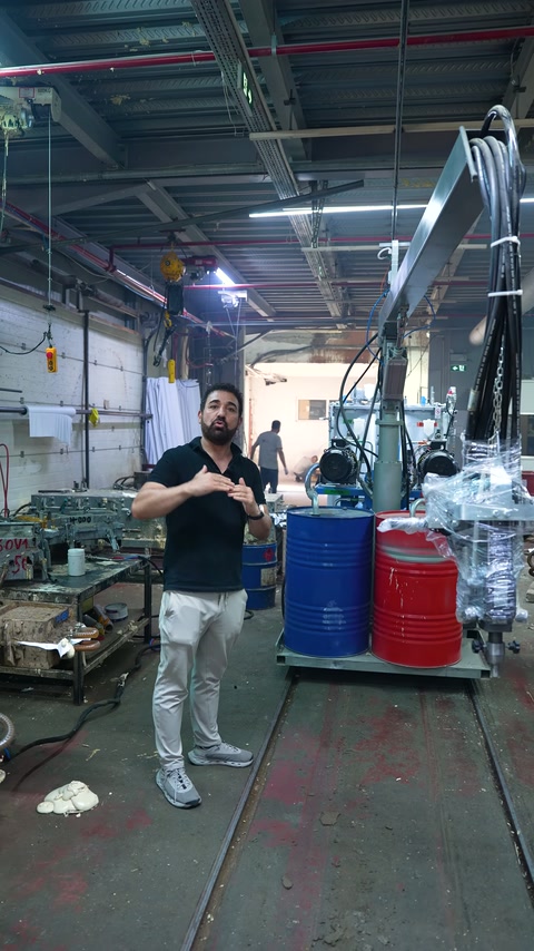 A factory worker presents a decorative product next to a large production machine.