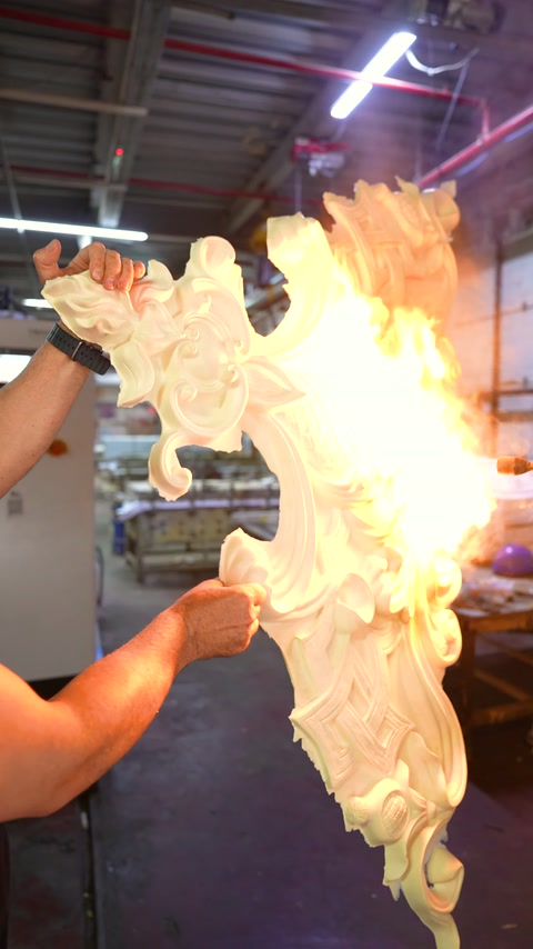 Flames spread across the surface of a carved embellished piece held in hand.