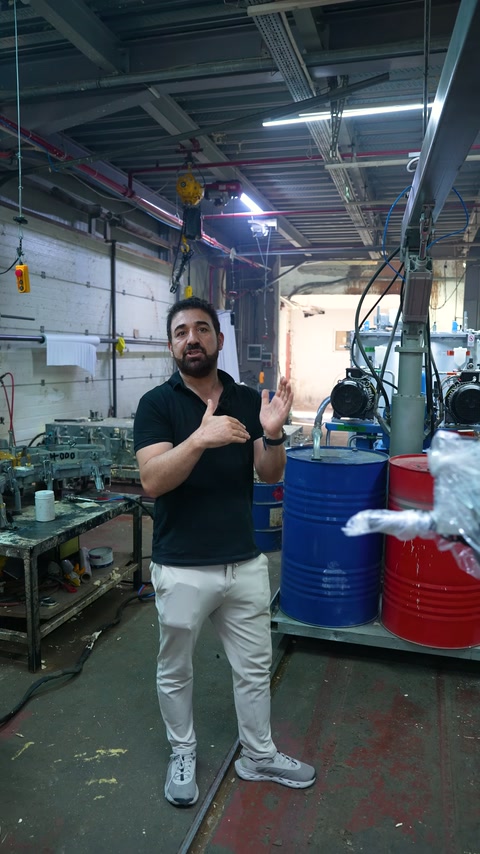 The server explains product details with hand gestures among factory equipment.