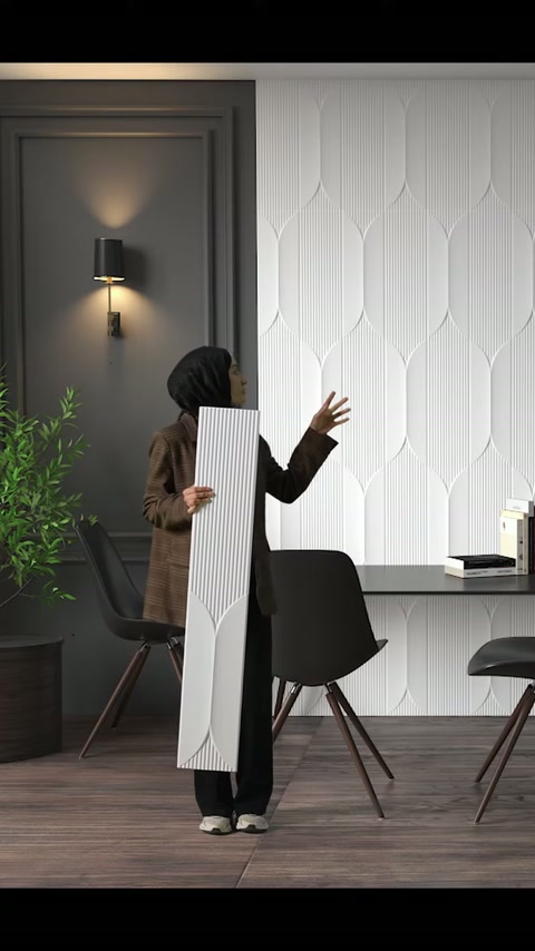 Si indica il rivestimento murale geometrico sullo sfondo mentre si tiene il lungo pannello decorativo.
