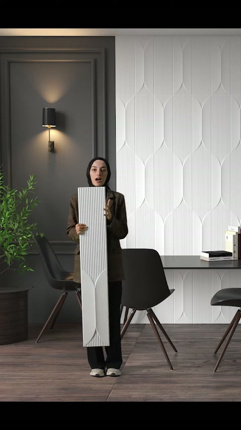 Il presentatore tiene saldamente il lungo pannello decorativo davanti al rivestimento murale moderno.