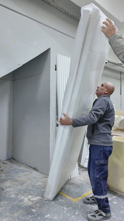 Two workers handle a long moulded section beside matching components