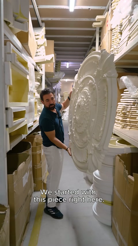 Large embossed medallion held vertically by designer in warehouse corridor.