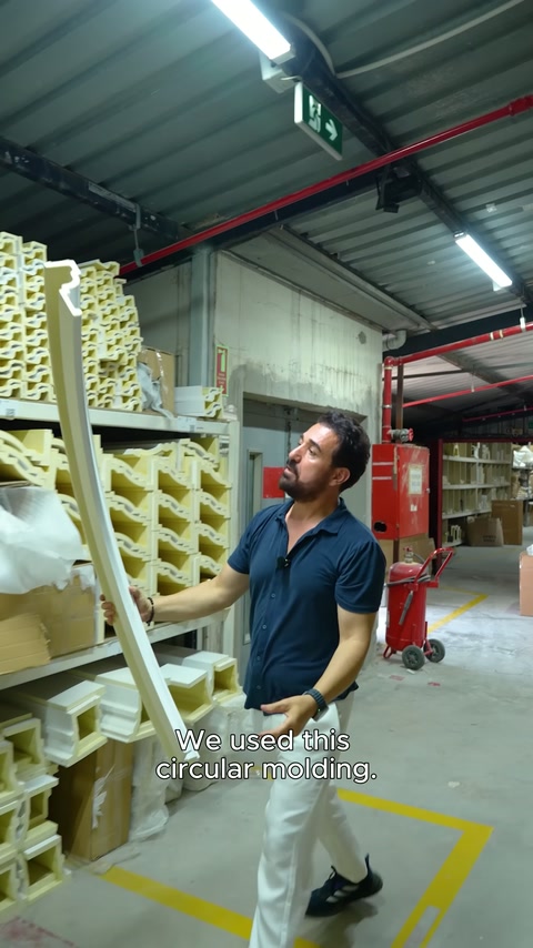 Circular polyurethane profile displayed vertically by hand in spacious warehouse area.