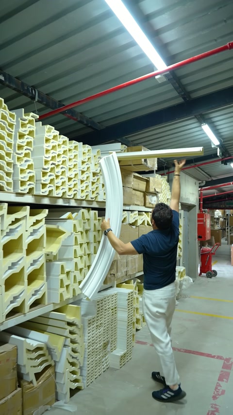 Long curved continuation profile lifted beside product racks in storage depot.