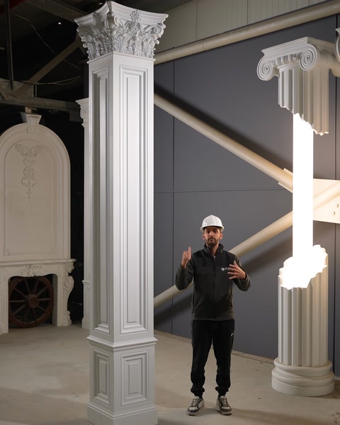 Artigiano che presenta una grande colonna scanalata in poliuretano con capitello corinzio