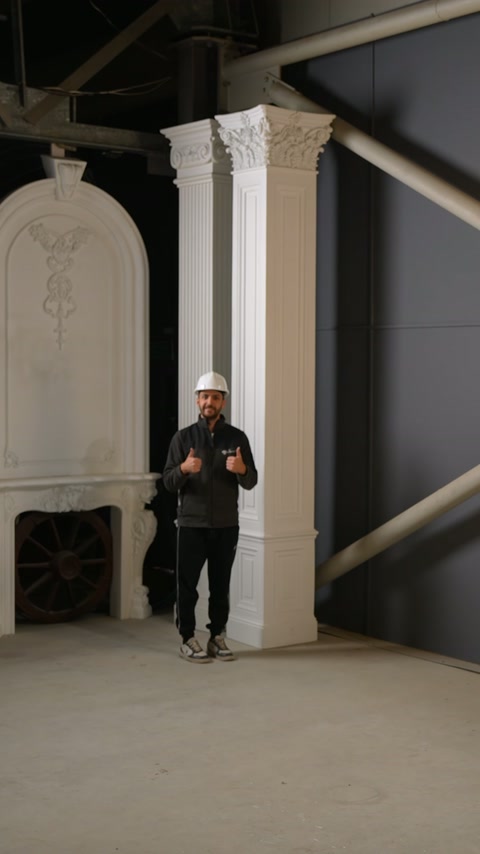Un presentatore si trova davanti a due colonne quadrate installate con capitelli ornati.