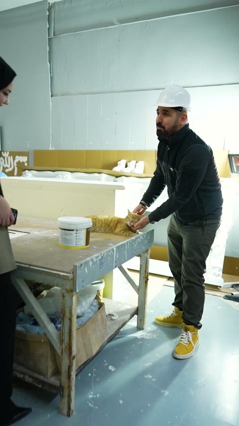 Un operaio con berretto presenta esempi di profilo bianco sul banco di produzione.