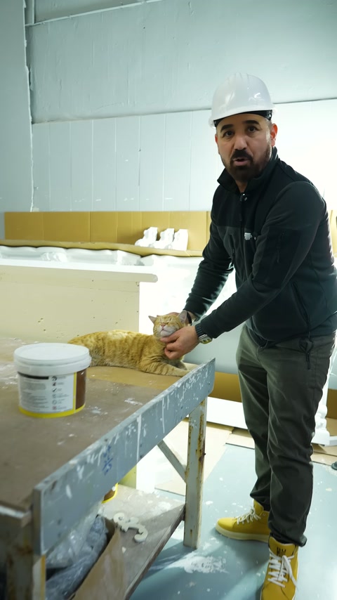 Un maestro con berretto mostra i pezzi decorativi bianchi nell'area di lavoro.