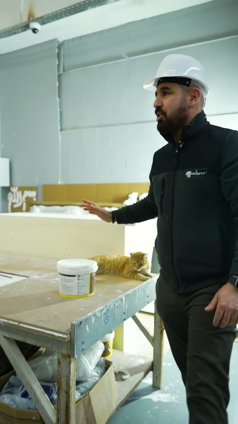 Un dipendente con berretto spiega le caratteristiche del profilo decorativo nell'area di produzione.