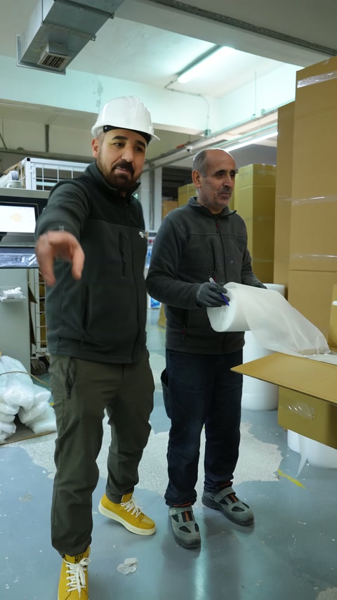 Due operai preparano il materiale di imballaggio in una scatola di cartone aperta.