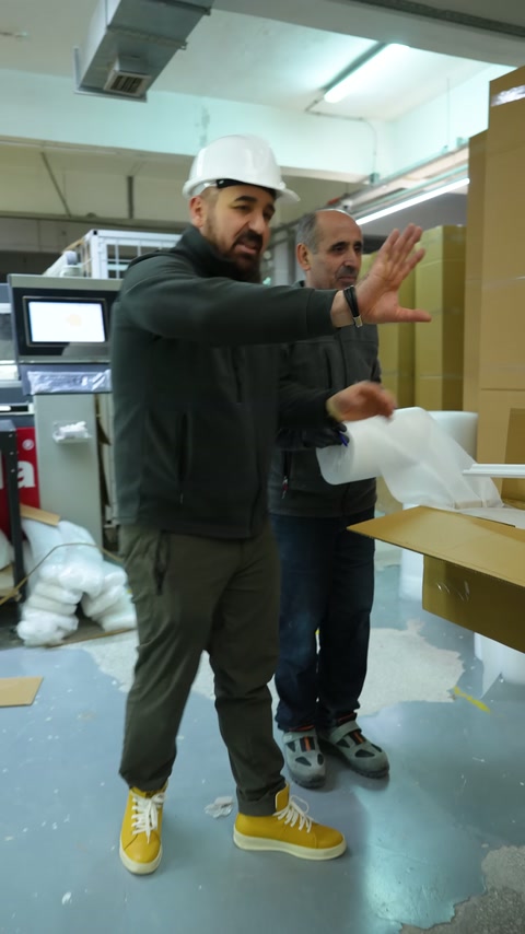 Un responsabile con berretto spiega il processo presso la stazione di imballaggio dei profili.
